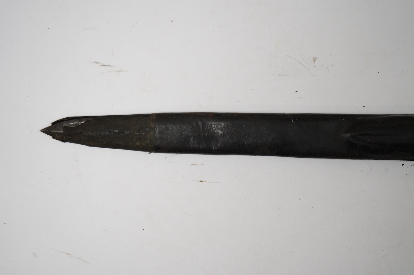 A 19th century Continental hunting hanger, blade cut with twin fullers, recurved brass crosspiece with acorn finials, staghorn grip (pommel missing), in its brass mounted leather scabbard, containing knife and fork (chap